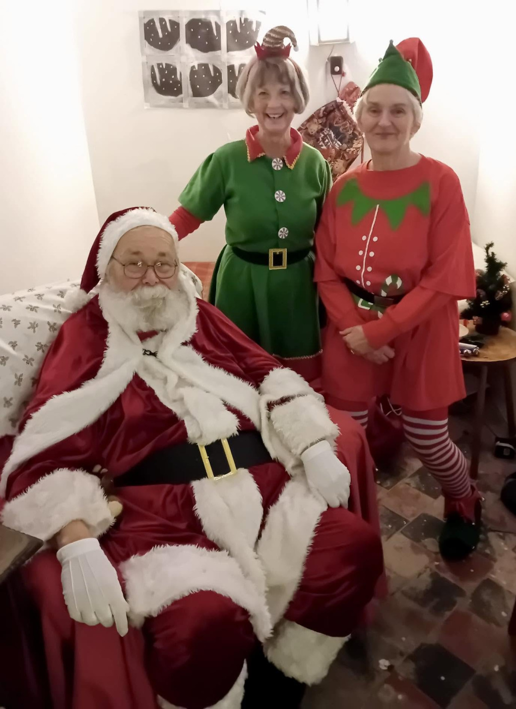 Santa with two older women dressed as elves